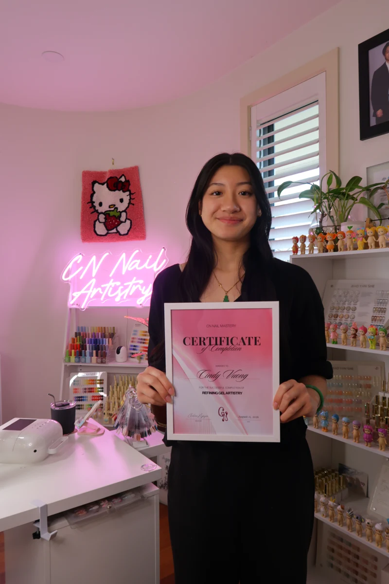 Course graduate holding her CN Nail Mastery certificate